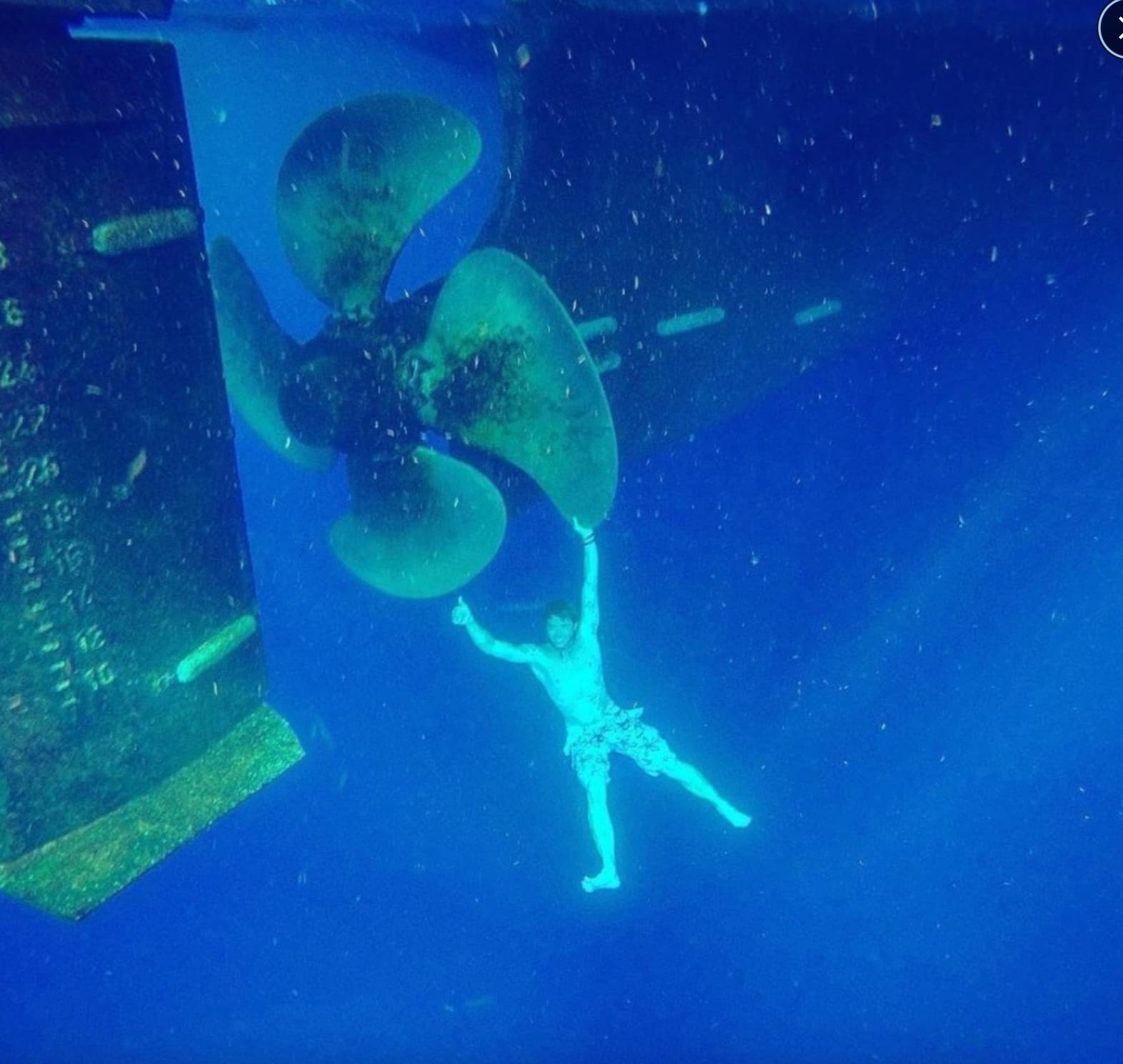 “Here's a swimmer holding on to a giant underwater boat propeller.”